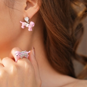 Detail of model wearing pink enamel poodle earrings and a matching bow ring set