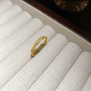 Detail of gold bamboo ring with white zircons on a white textured jewelry box