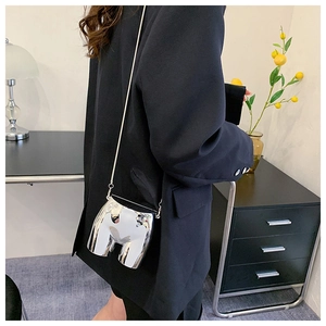 Detail of silver mirrored abstract crossbody bag with fine metal chain on a black blazer
