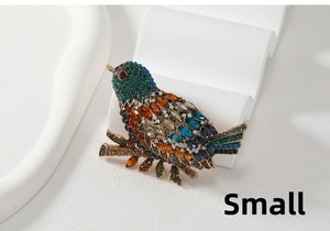 Detail of small vintage magpie brooch featuring colorful marquise rhinestones on a gold branch