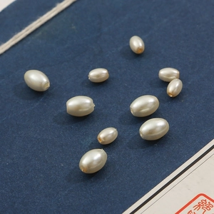 Perle ovali in finta madreperla crema per gioielli fai da te su carta blu vintage