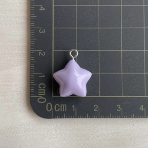 Close-up of a light purple resin star pendant with a metal ring on a scale mat