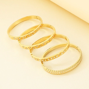 Detail view of 18K gold plated titanium bangles with diamond-set patterns and textures