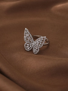 Macro shot of sparkling butterfly ring with zircon wings on a premium silk background
