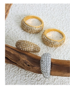 Detail of wide band gold and silver titanium rings set with Czech rhinestones on sand