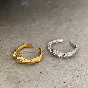 Macro shot of silver and gold C-shaped ear cuffs with organic molten lava texture
