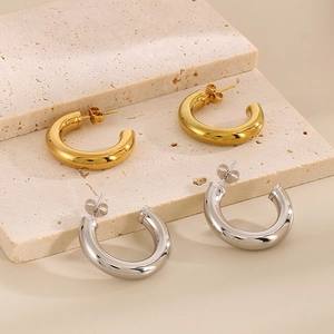 Orecchini a cerchio a C in oro e argento su eleganti vassoi in pietra travertino beige
