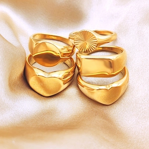 Macro shot of five minimalist gold heart and geometric rings on champagne silk