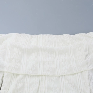 Detailed macro view of white floral lace texture on the off-shoulder neckline of the dress