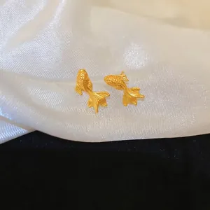 Boucles d'oreilles poisson d'or plaquées or avec texture givrée sur fond de soie blanche