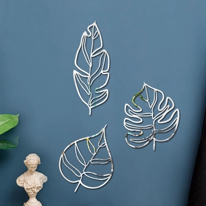 Détail des stickers muraux effet miroir argenté en forme de feuilles sur mur bleu
