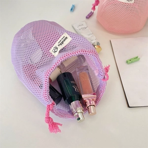 Detailed macro view of purple mesh travel pouch with pink drawstring and skincare products