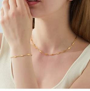 Close-up of golden necklace and bracelet set featuring detailed tennis racket charms