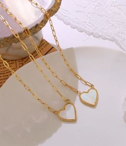 Detail of gold paperclip chain necklace with white mother-of-pearl heart pendant