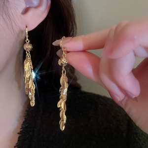 Detail of golden metal leaf fringe earrings with beaded tops and shimmering sequins