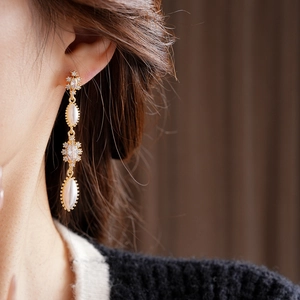 Close-up of vintage tassel earrings with pearls and gold finish on a model's ear