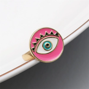 Macro view of pink enamel evil eye ring detail with golden alloy frame and blue iris iris