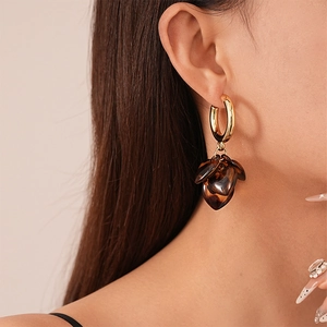Elegant leopard print acrylic heart drop earrings with gold hoops worn by model