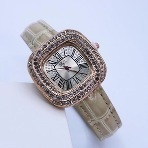 Close-up of square rose gold watch with beige leather strap and rhinestone bezel