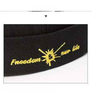 Detail of black canvas docker hat featuring yellow Freedom embroidery and sun logo