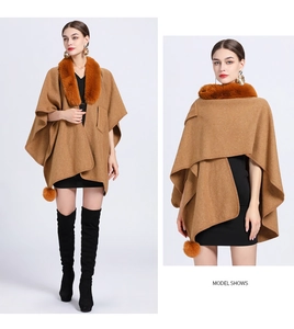 Detail of camel knit poncho with faux rabbit fur collar and decorative pom-poms