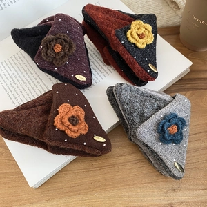Close-up of four plush knit triangular flower hair clips on a vintage book surface