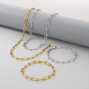 Set of gold and silver square link chain necklaces and bracelets on gray pedestals