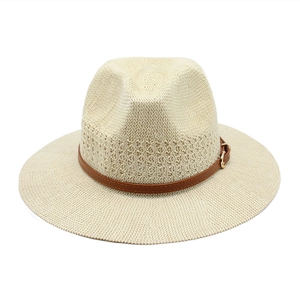 Detailed weave texture of cream straw hat with brown leather belt and gold metal buckle