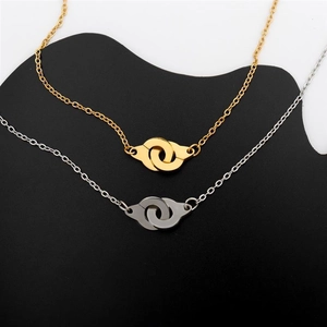 Detailed close-up of interlocking handcuff pendants in polished gold and silver finishes