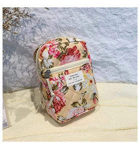 Detail of floral quilted cosmetic bag featuring beige cotton fabric and zipper pockets