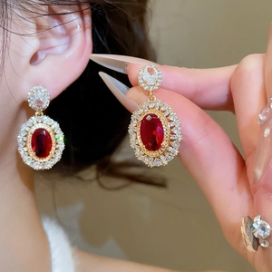 Detailed macro of vintage gold-plated drop earrings with a red oval gem and zircons