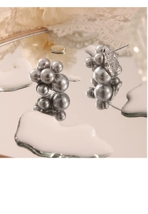 Macro detail of dark grey cluster pearl stud earrings on a reflective mirror surface