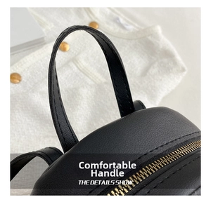 Detail of black pebbled leather backpack showing sturdy top handle and golden metal zipper