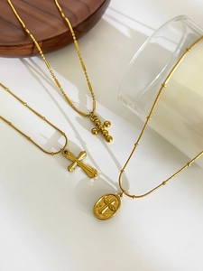 Detailed view of three vintage gold titanium cross necklaces on elegant display