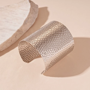 Macro detail of silver geometric hammered texture on open cuff metal bracelet