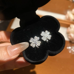 Macro detail of silver four-leaf clover stud earrings with sparkling cubic zirconia inlay