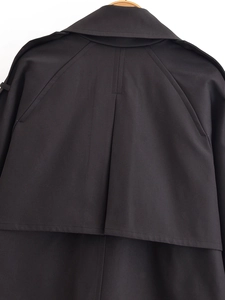 Macro shot of double-breasted black trench coat showing collar and back rain shield detail