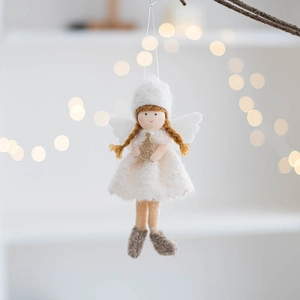 Detail of felt angel girl ornament with golden tree and white wings in warm lighting