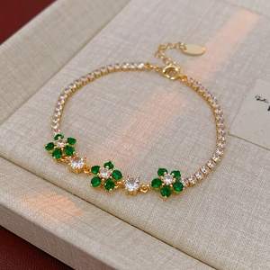 Macro shot of gold flower bracelet with green zircon petals and adjustable chain link