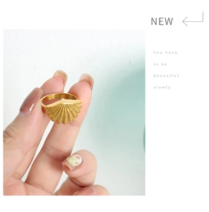 Detailed view of an elegant gold seashell ring with textured finish on model's hand