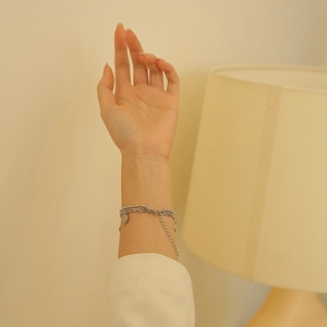 Detailed view of layered silver beaded chain bracelet with adjustable link on female wrist