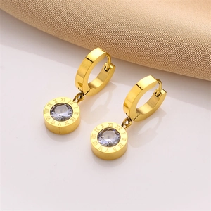 Detail of gold roman numeral earrings with a single sparkling round clear zircon stone