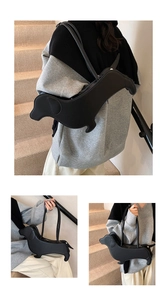 Detail of dachshund-shaped black leather tote bag worn as a shoulder and handbag
