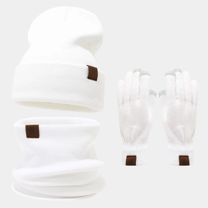 Detailed close-up of white knit beanie, scarf, and gloves with snowflake leather patches