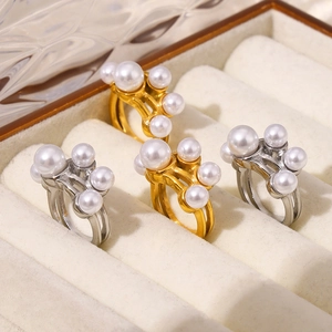 Set van vier goud- en zilverkleurige holle ringen met witte parels in een juwelendoos