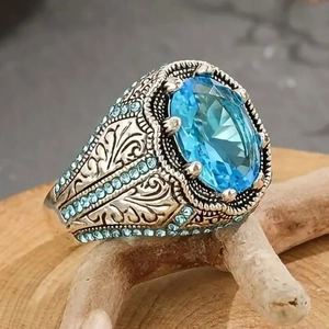 Anello vintage in argento con gemma blu ovale e intricati motivi floreali incisi