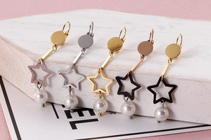 Détail de cinq paires de boucles d'oreilles étoiles colorées avec perles sur pierre blanche