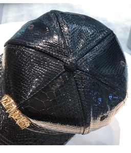 Detail of laser PU leather flat brim hat with snake texture and gold metal spikes