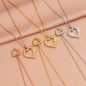 Macro shot of heart jewelry sets in gold, rose gold and silver on pink silk background