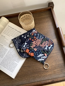 Close-up of navy linen pouches with floral embroidery and silver zipper rings